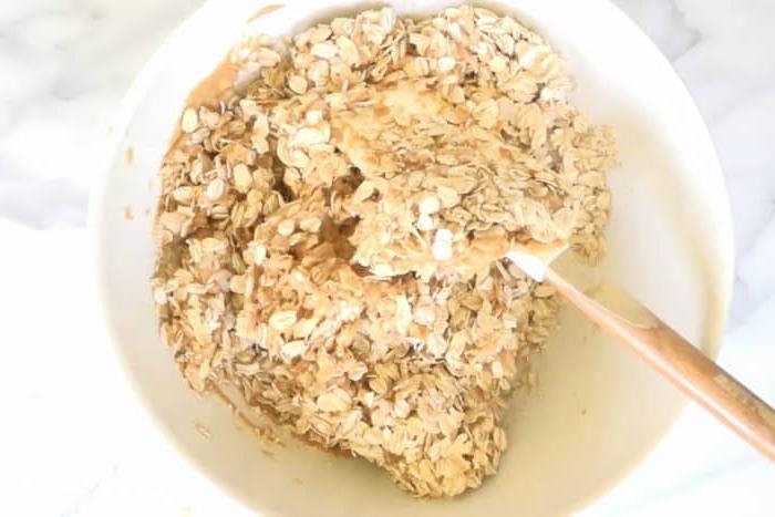 Granola, Reis, Erdnussbutter und Honig werden mit einem Spatel vermischt.
