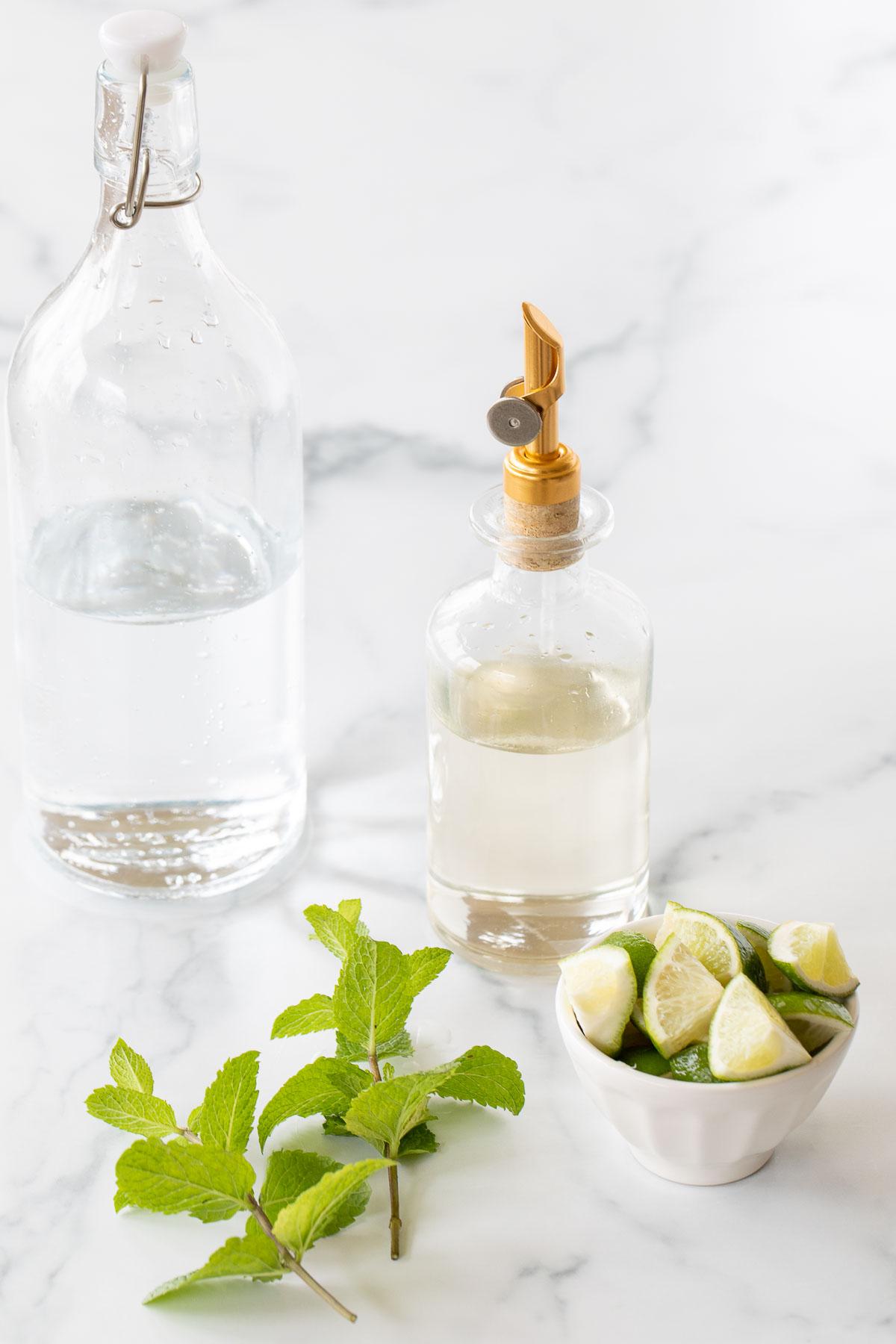 Alkoholfreier Mojito 4 Zutaten für einen Virgin Mojito Mocktail auf einer weißen Arbeitsplatte.