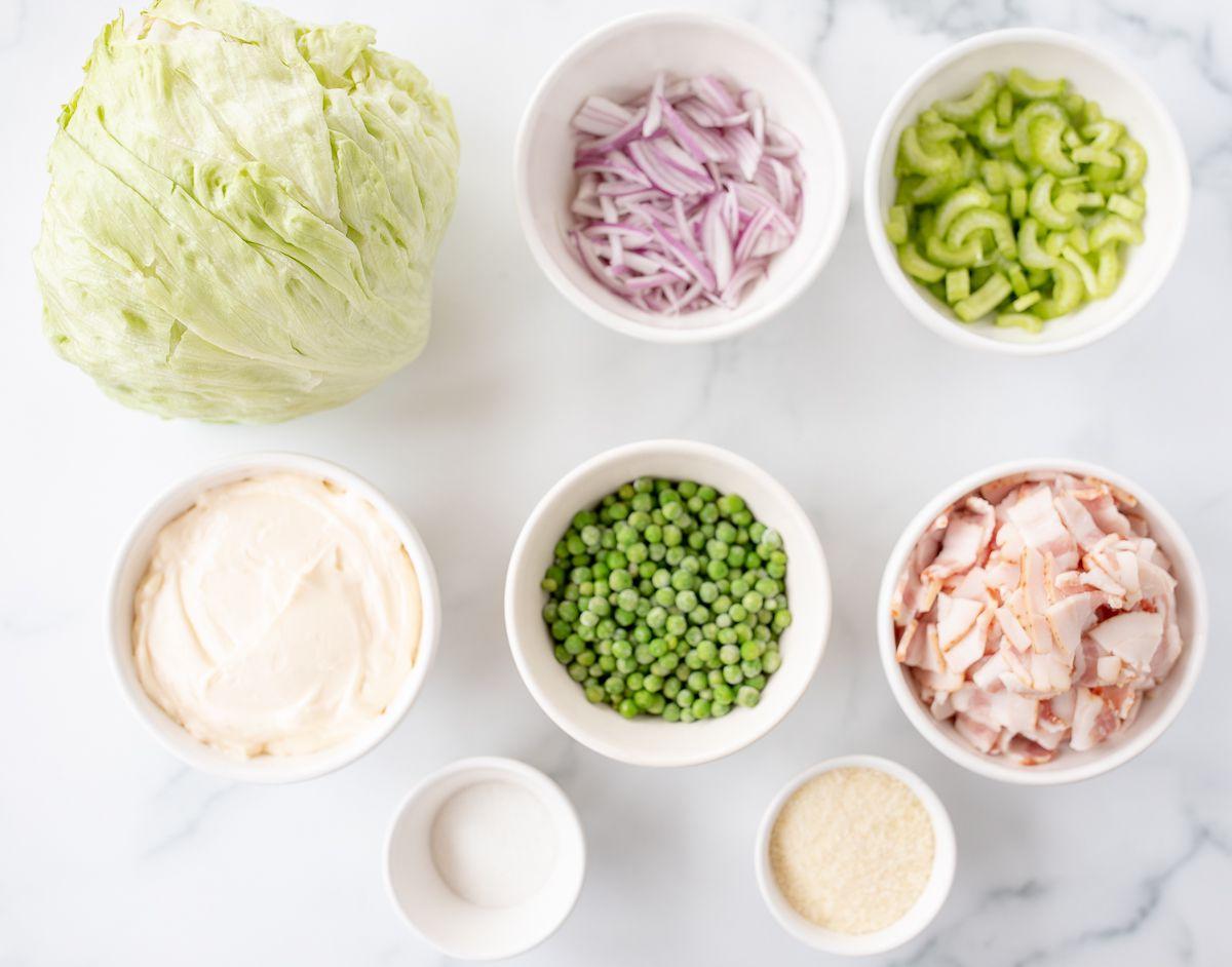 Siebenschichtsalat 5 Zutaten für Sieben-Schicht-Salat auf einer Marmorfläche ausgebreitet.