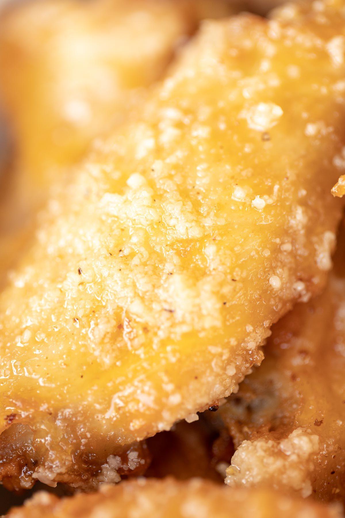 Knoblauch-Parmesan-Hähnchenflügel 5 Ein einzelner, goldbrauner Hähnchenflügel in Nahaufnahme, bereit zum Servieren in einer eleganten Schüssel