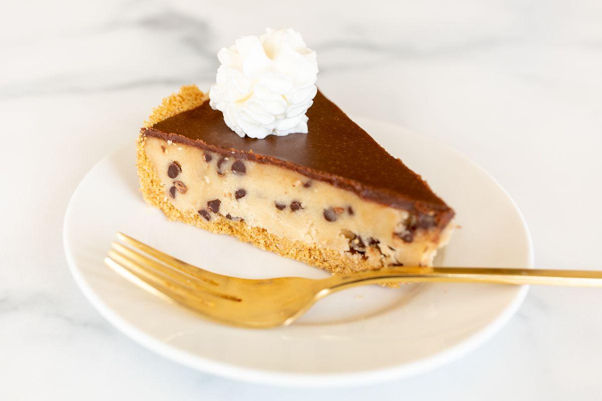 Keksteigkuchen 5 Ein weißer Teller mit einem Stück Keksteig-Kuchen und einer goldenen Gabel.