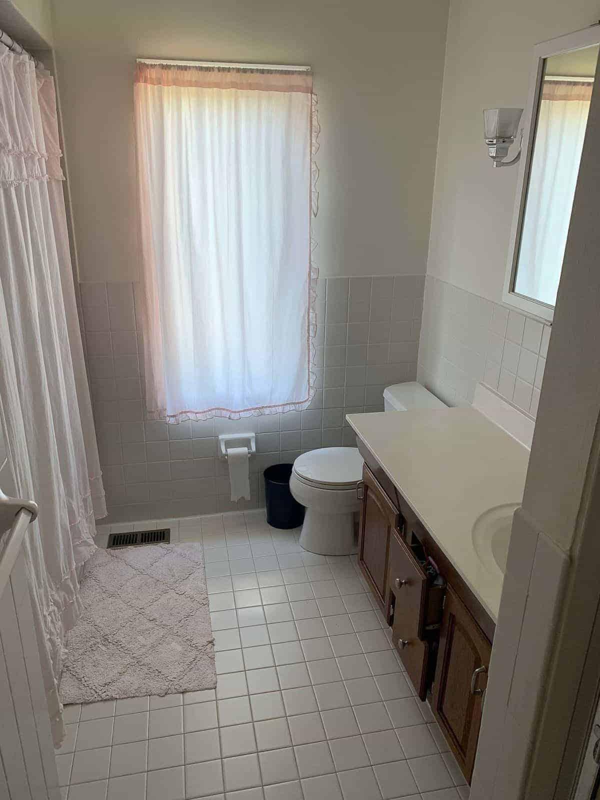 So erstellen Sie ein Spa-Bad zu Hause 5 Veraltetes Badezimmer aus den 70ern mit dunklem Schrank, alten Fliesen und unzureichender Beleuchtung.