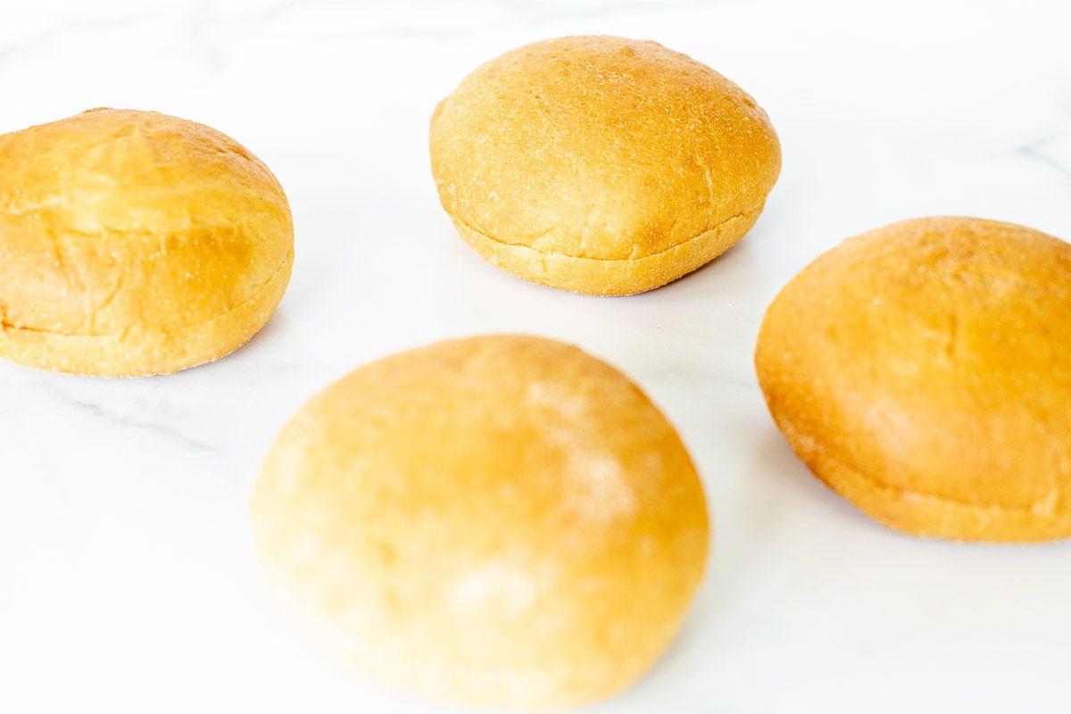 Warum man Burgerbrötchen rösten sollte 5 Hamburger Buns auf einer Marmoroberfläche ausgelegt