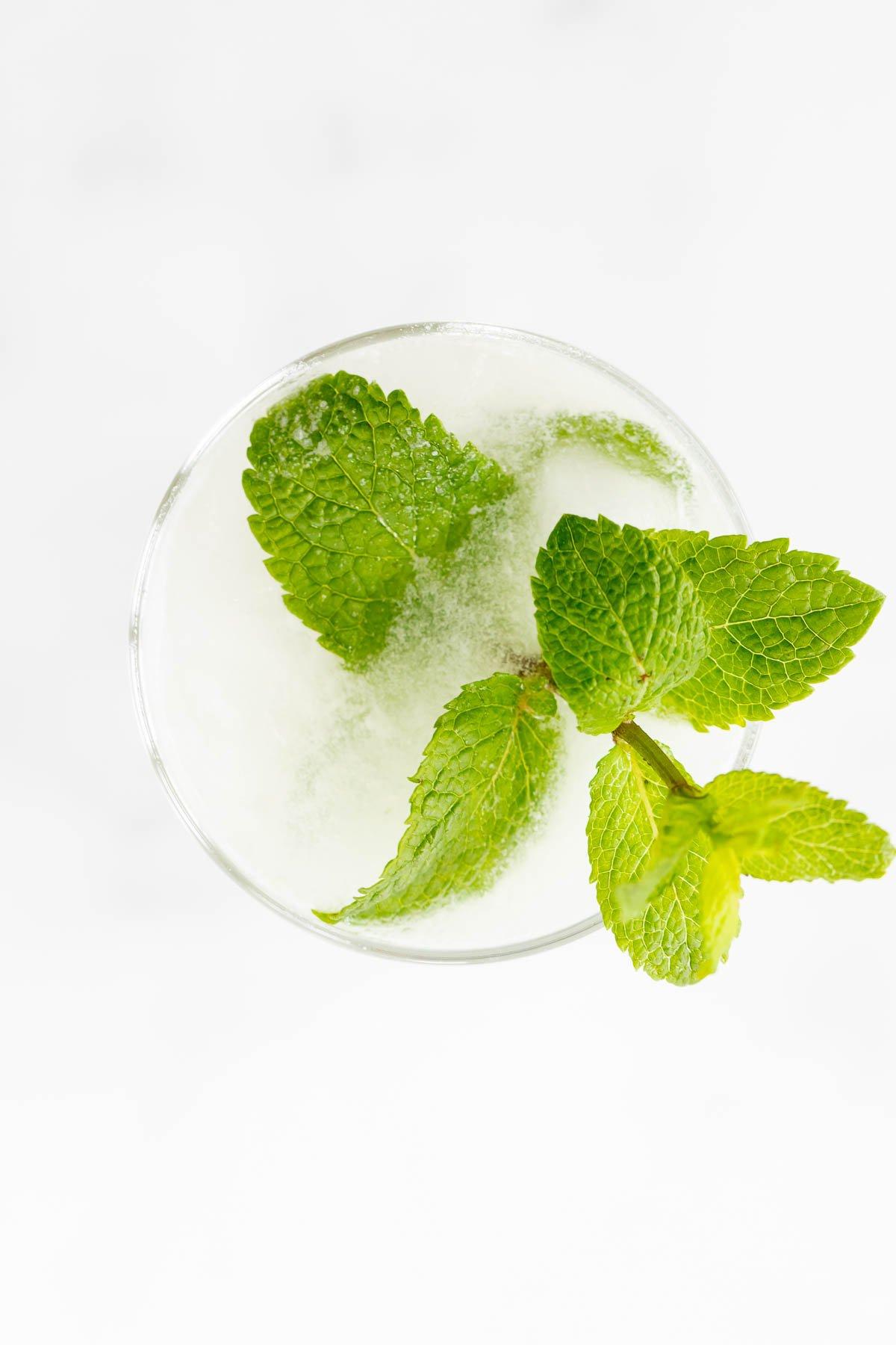 Kokosnuss-Mojito 5 Ein Kokos-Mojito, garniert mit Minze, auf einer Marmorfläche.