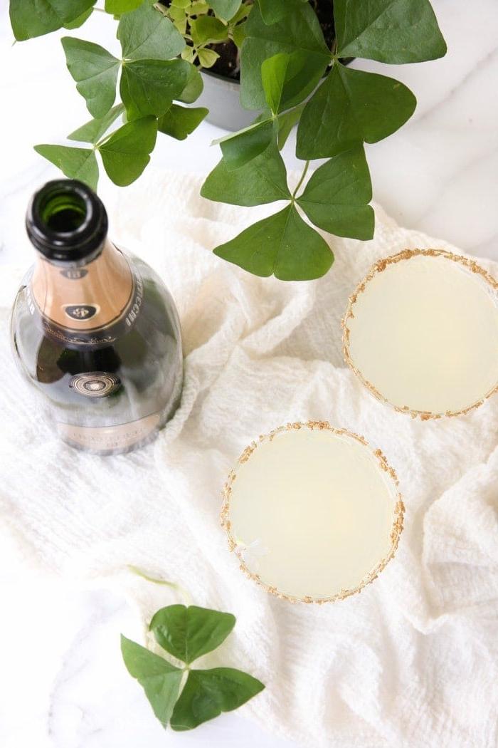 Shot of Gold: Ihr festlicher Drink für den irischen Feiertag Zwei sprudelnde Limonaden-Cocktails neben einem Kleeblatt für den St. Patrick's Day