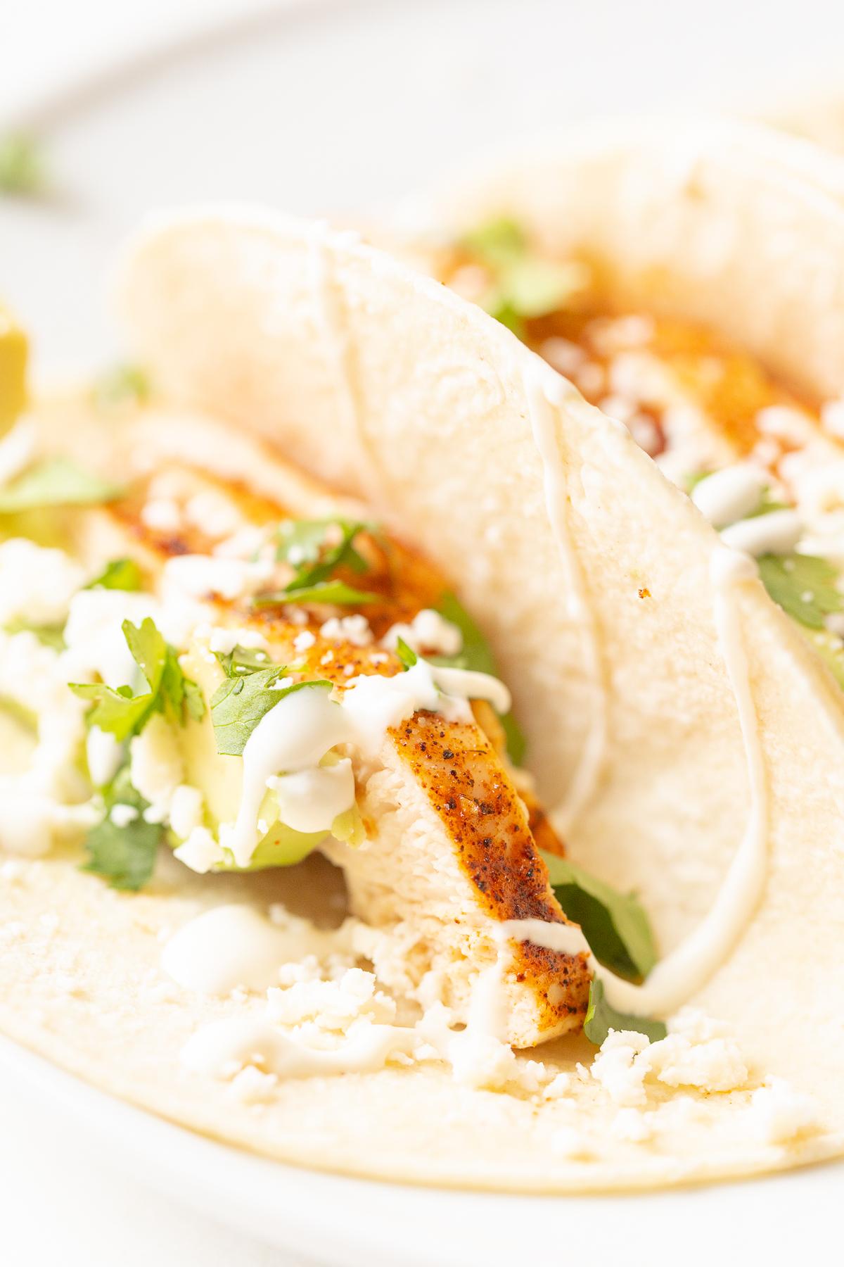Weiche Hähnchen-Tacos 5 Hähnchen-Tacos in Mais-Tortillas auf einer weißen Oberfläche.