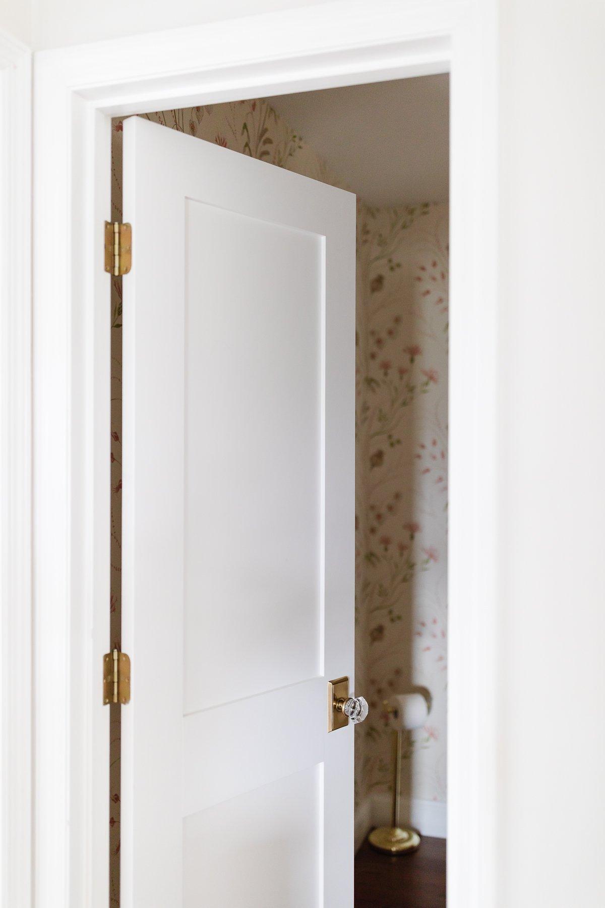 Eine weiße Shaker-Tür in einem eleganten Raum mit einer auffälligen floralen Tapete, die die Vielseitigkeit des Designs unterstreicht.
