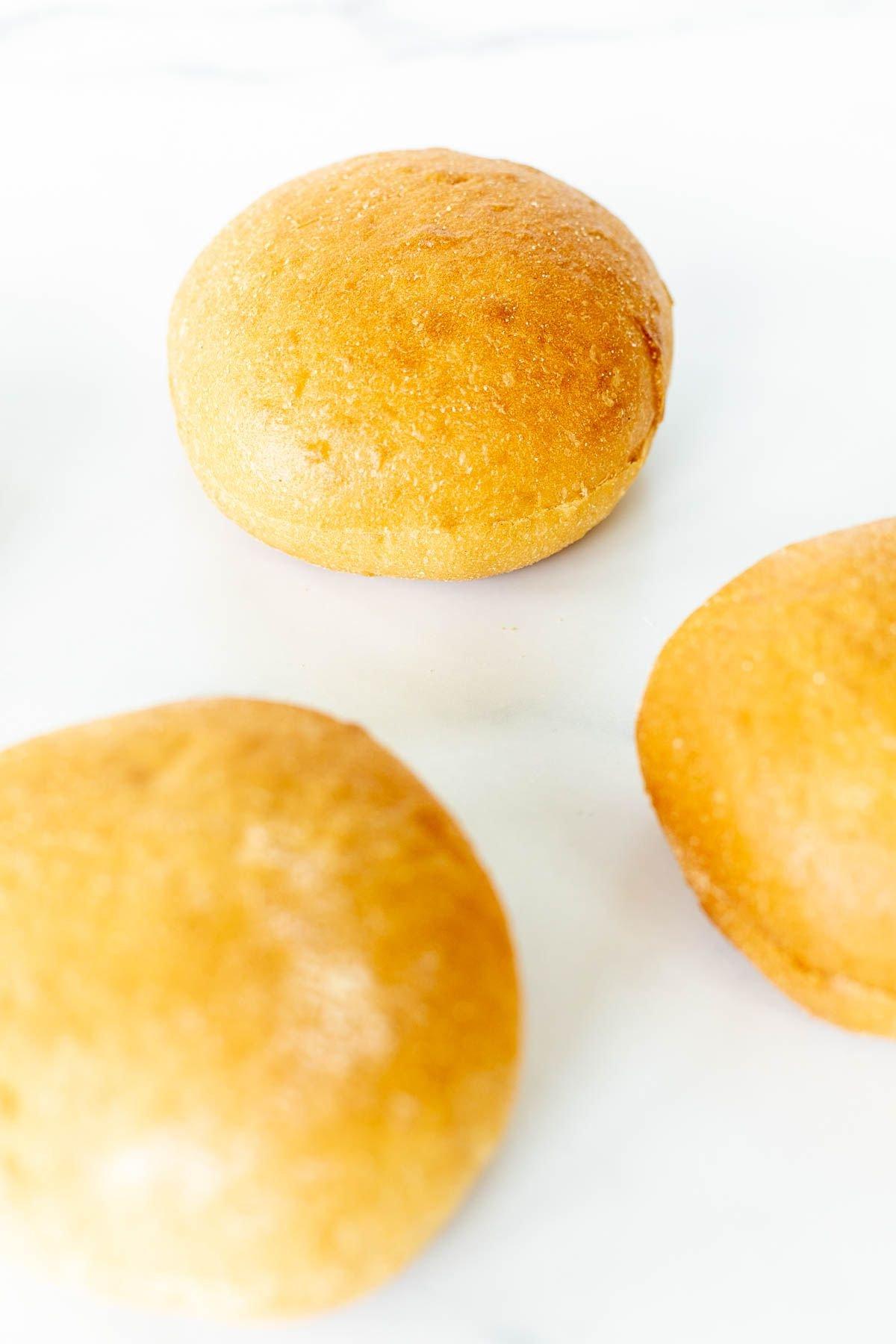Warum man Burgerbrötchen rösten sollte 6 Hamburger Buns auf einer Marmoroberfläche ausgelegt