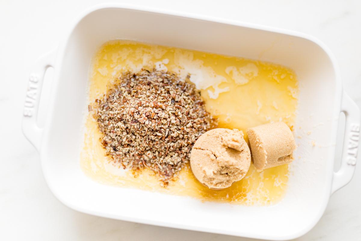 Brauner Zucker, Pekannüsse und Butter in einer weißen Auflaufform.