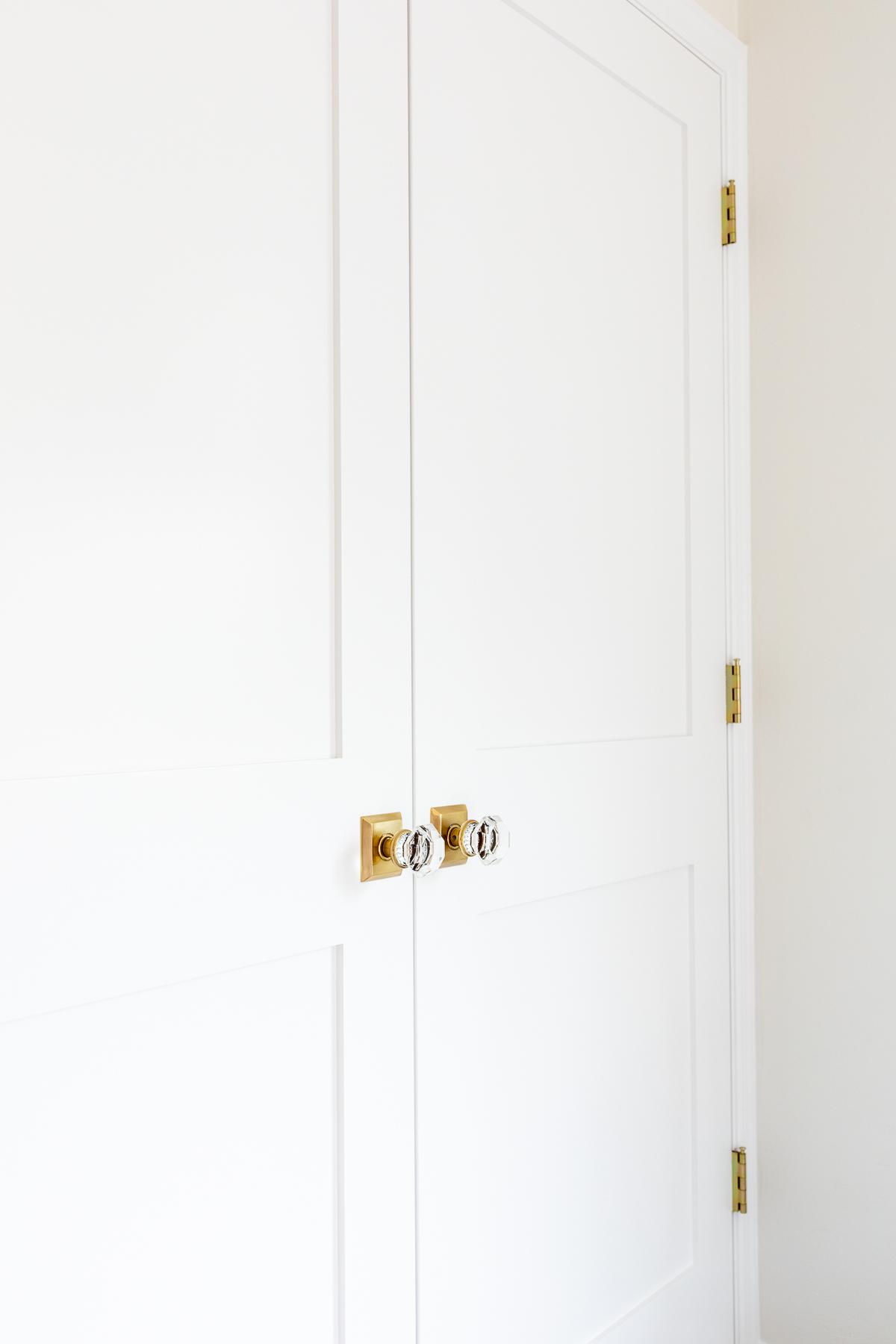 Innentüren streichen 6 Eine geschlossene weiße Tür, perfekt gestrichen mit Messinggriffen, für ein elegantes Interieur.