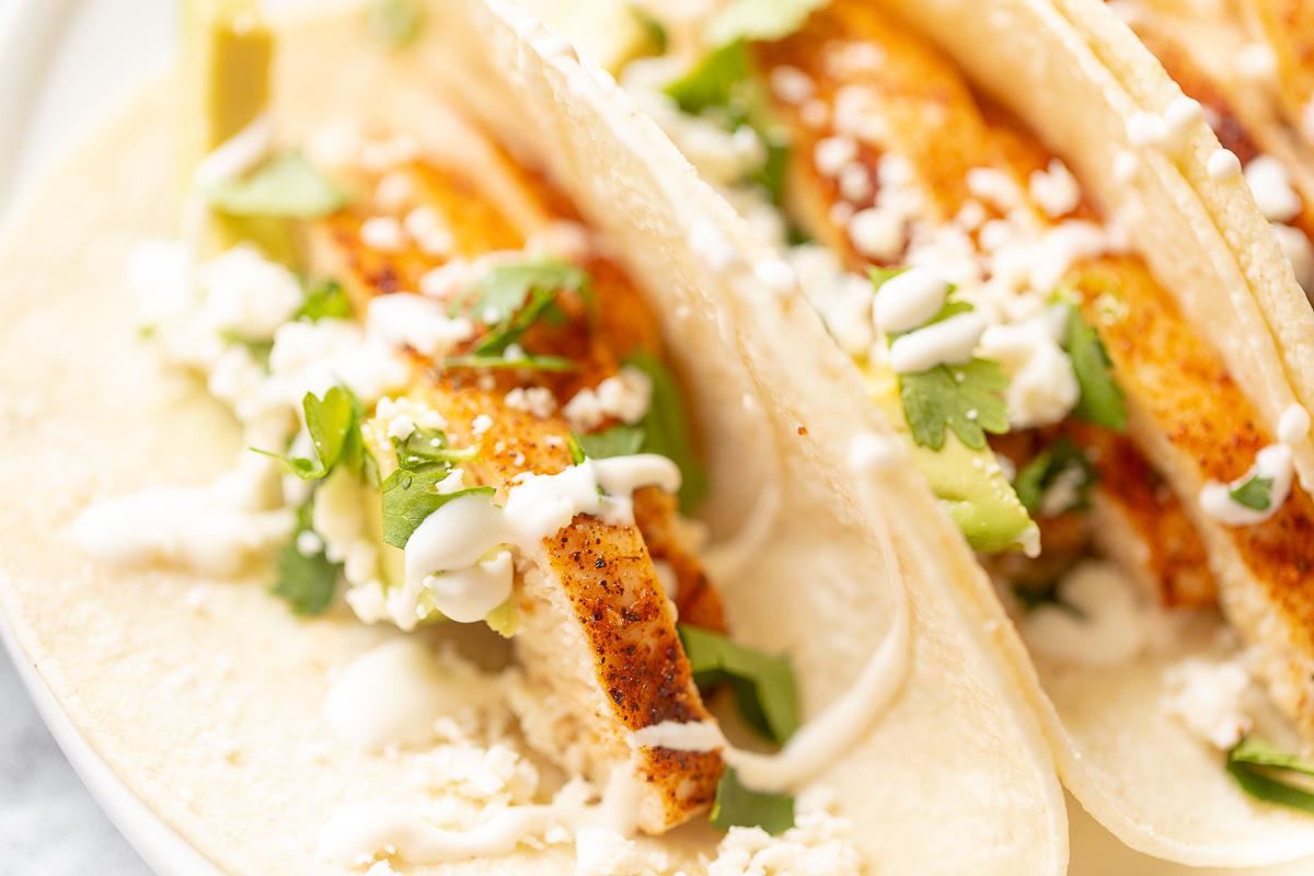 Weiche Hähnchen-Tacos 6 Hähnchen-Soft-Tacos in Mais-Tortillas auf einer weißen Oberfläche.