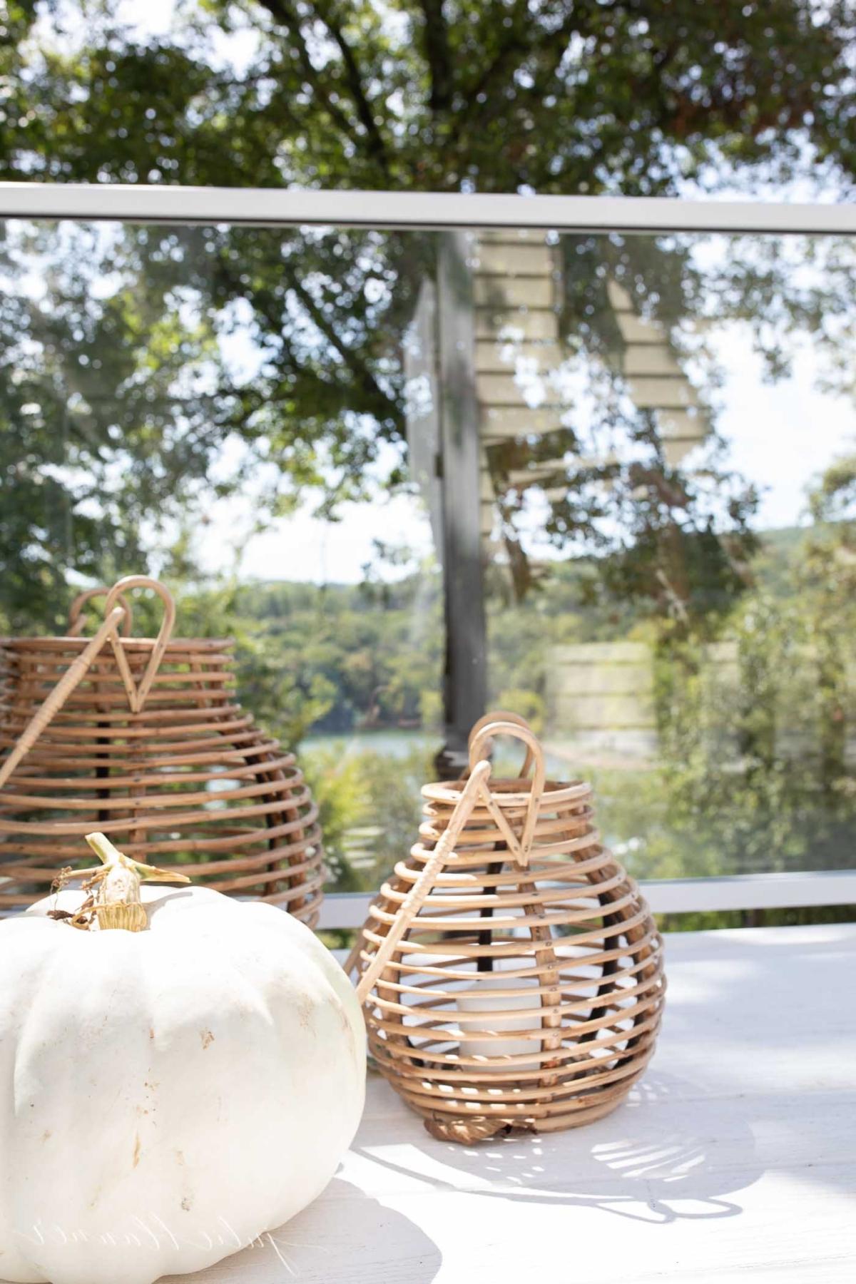 Rattanlaternen und ein weißer Kürbis auf einer herbstlichen Veranda.