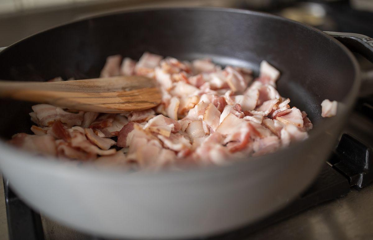 Siebenschichtsalat 6 Gehackter Speck in einer Bratpfanne kochen