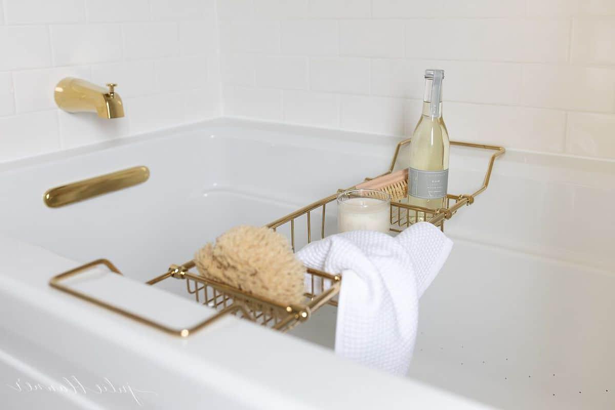 So erstellen Sie ein Spa-Bad zu Hause 7 Luftsprudelbad mit Messingarmaturen und einem Messing-Badewannentablett, gefüllt mit Spa-Produkten.