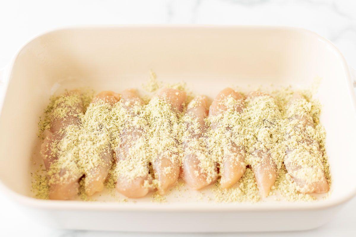 Hähnchenfilets, gewürzt in einer weißen Auflaufform, bereit zum Backen.