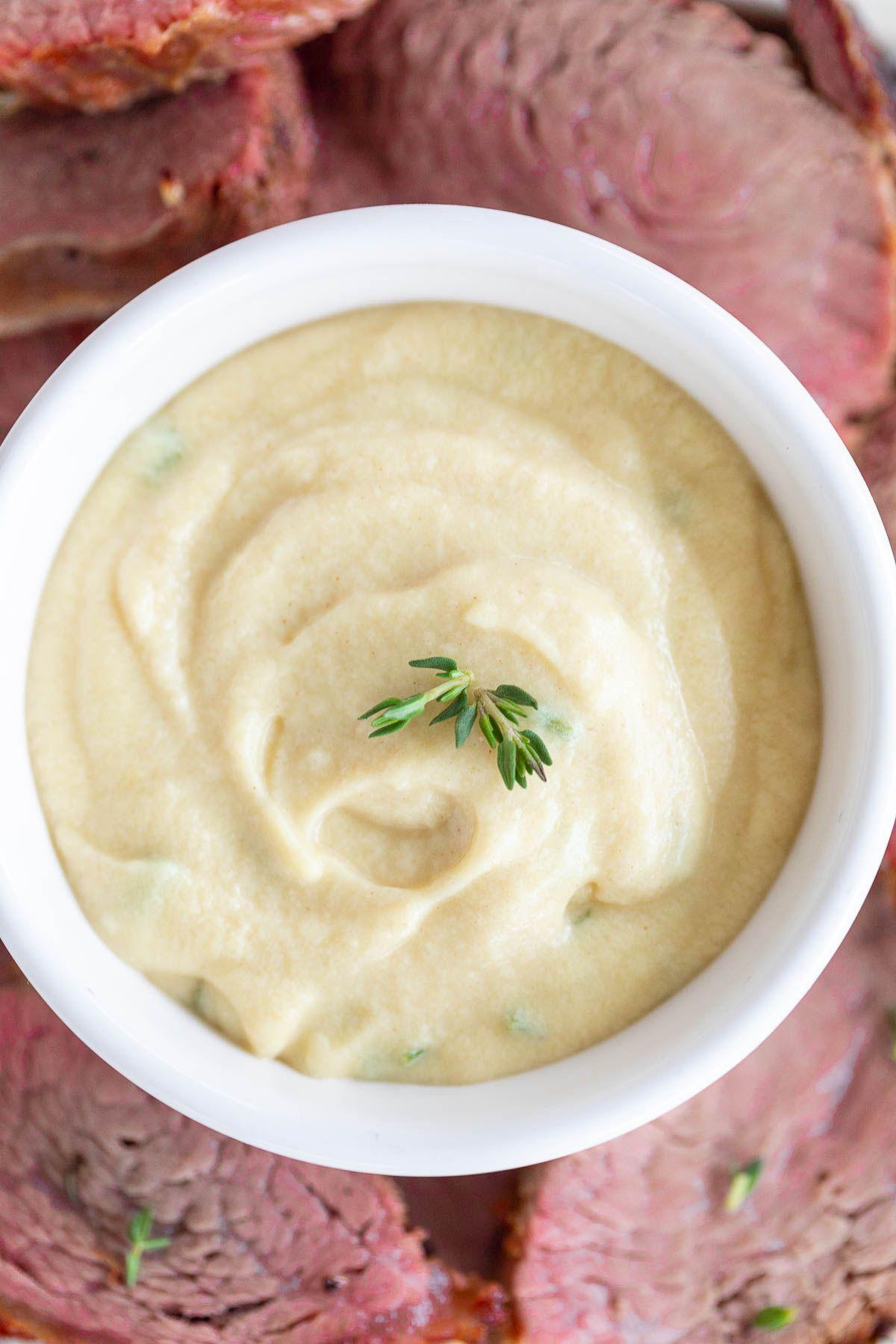 Eine weiße Schale voller Dijon-Sauce, umgeben von Rinderfilet.