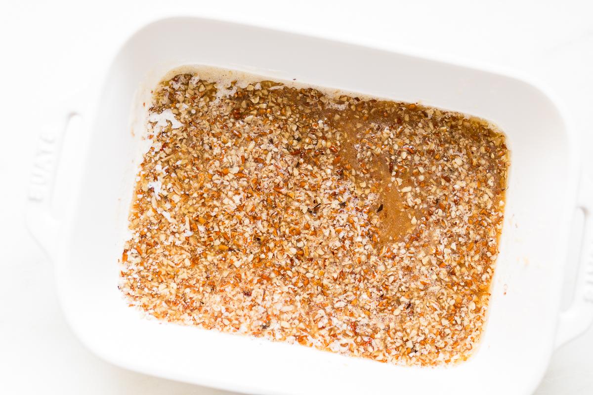 Eine weiße Auflaufform gefüllt mit Pekannüssen und Karamellsauce.