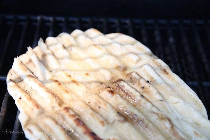 Pizzateig auf einem Außengrill ausgebreitet, belegt mit Zimt und braunem Zucker