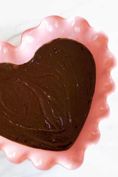 Herzförmiges Brookie-Dessert in einer rosa gewellten Schale auf einer Marmoroberfläche.
