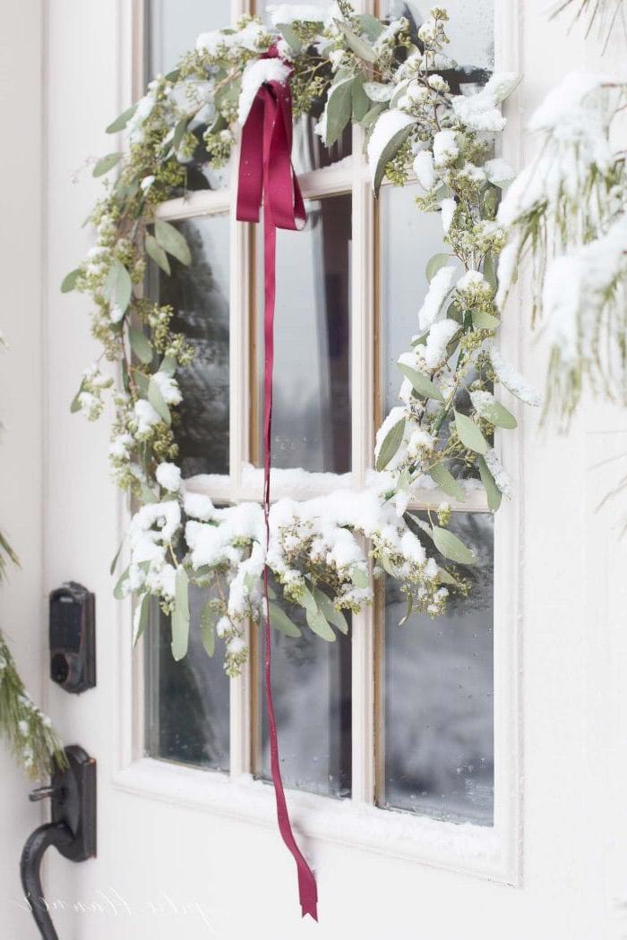 Weihnachtliche Türdekorationen 7 Weihnachtskranz mit Schnee bedeckt vor einer Tür