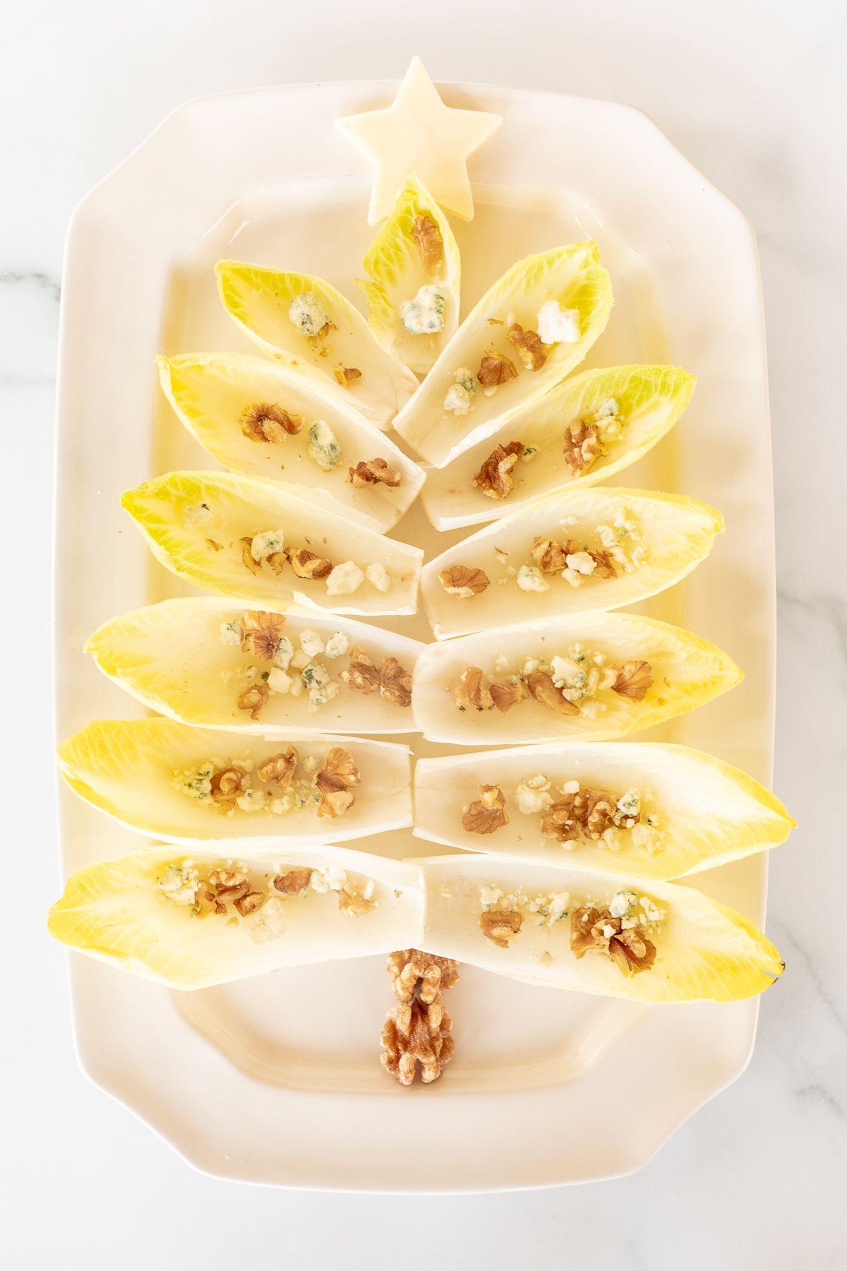 Ein Chicorée-Salat in Form eines Weihnachtsbaums auf einer weißen Platte angerichtet.