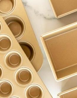 **Unglaublicher Butterscotch-Kuchen** 8 Eine Auswahl an goldfarbenen Kuchenformen, Kastenformen und Muffinformen auf einer Marmoroberfläche.