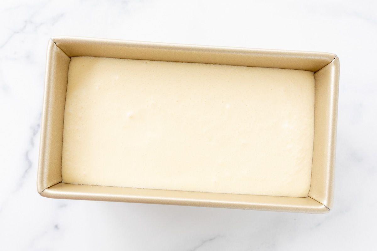 Flüssiges Orangen-Sherbet in einer goldene Brotkastenform, bereit zum Einfrieren