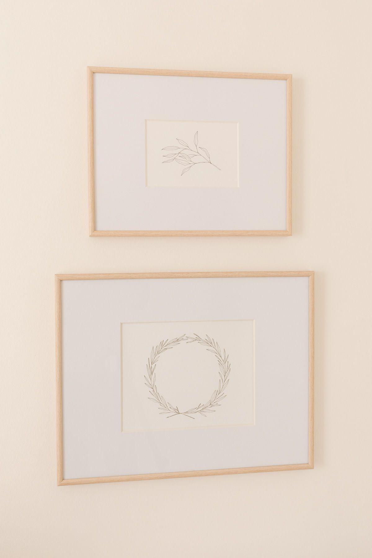 Druckbare Weihnachtskunst in Rahmen an einer cremefarbenen Wand.
