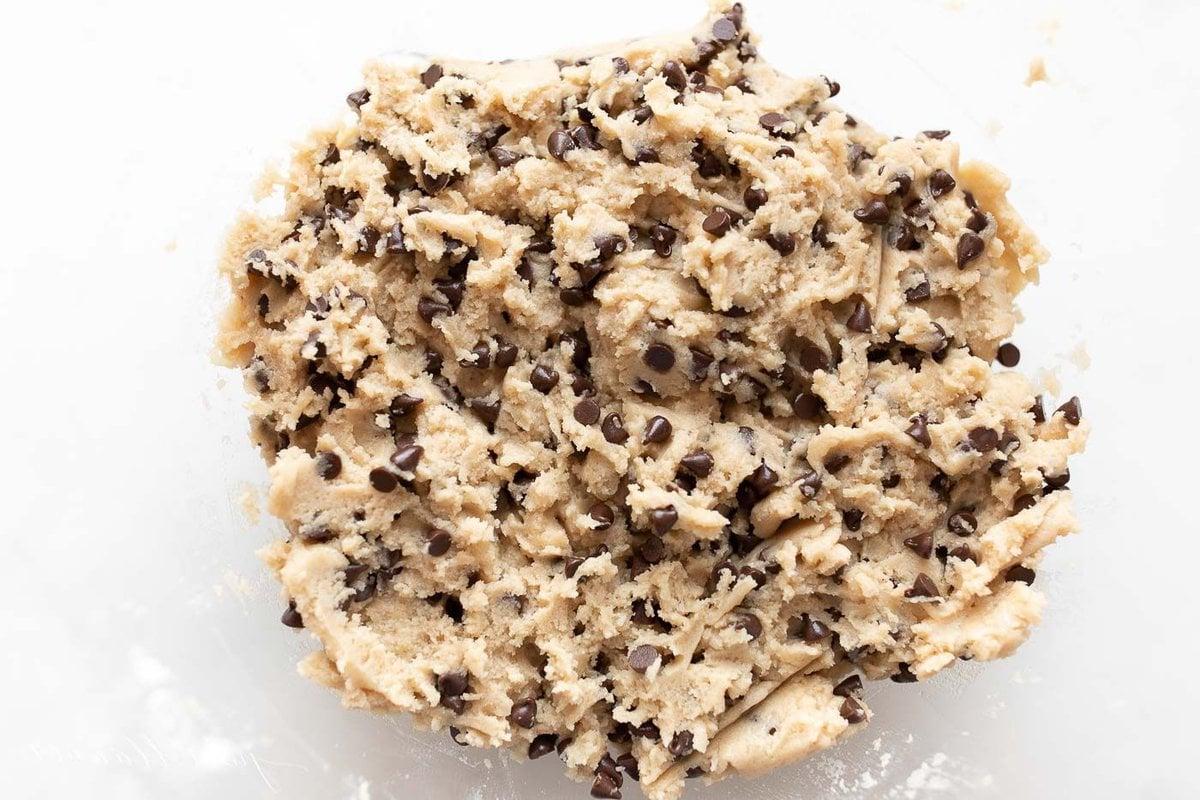 Essbarer Keksteig mit Schokochips 3 Eine kleine weiße Schale gefüllt mit essbarem Keksteig und Schokostückchen auf einer Marmoroberfläche