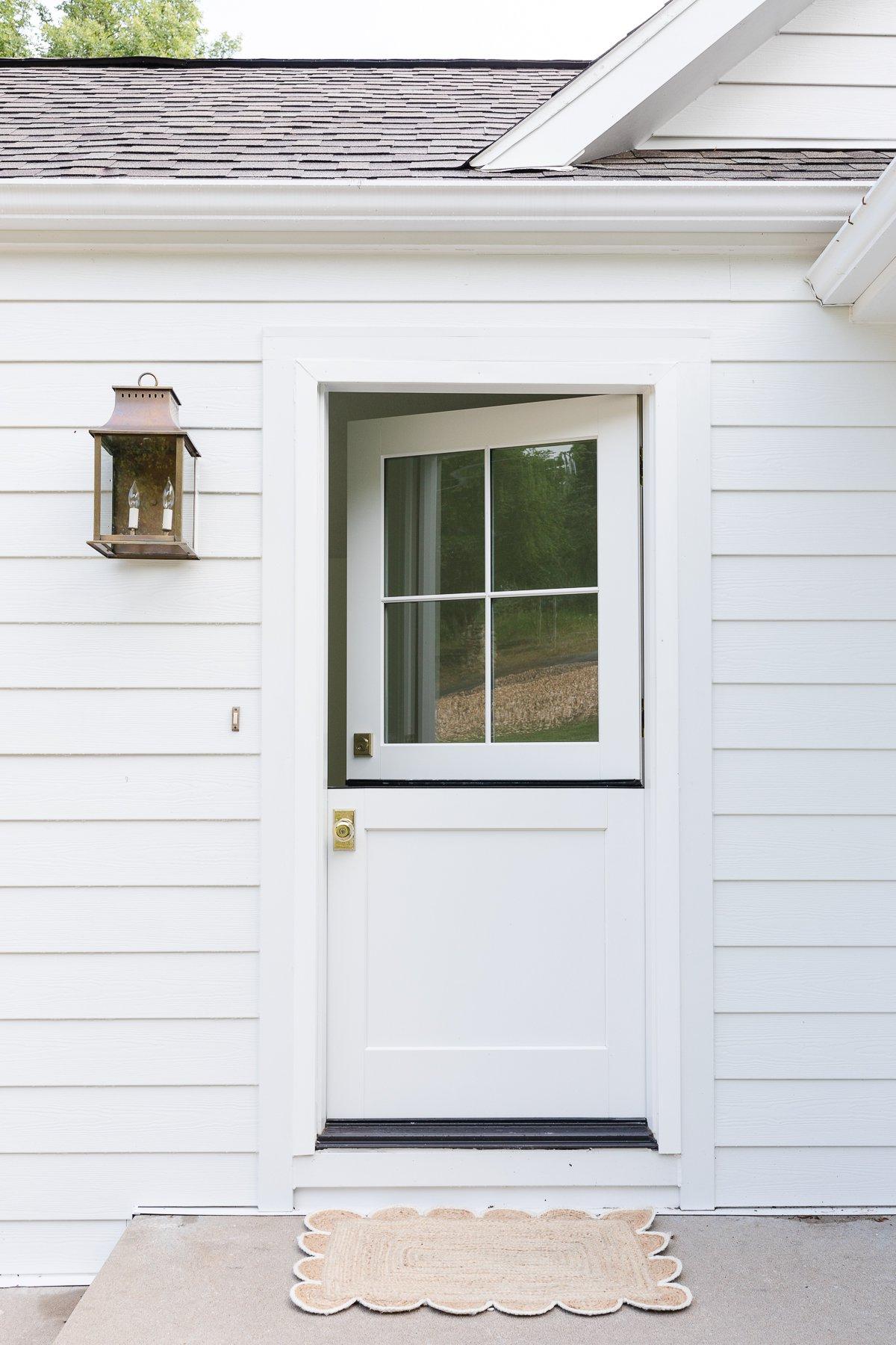 Die Hollandtür 8 Eine weiße Holländische Tür an einem weiß verkleideten Cottage.