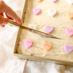 Goldenes Messer schneidet Zuckerkeks-Riegel mit Buttercreme-Glasur