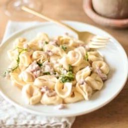 Tortellacci auf weißem Teller mit goldener Gabel