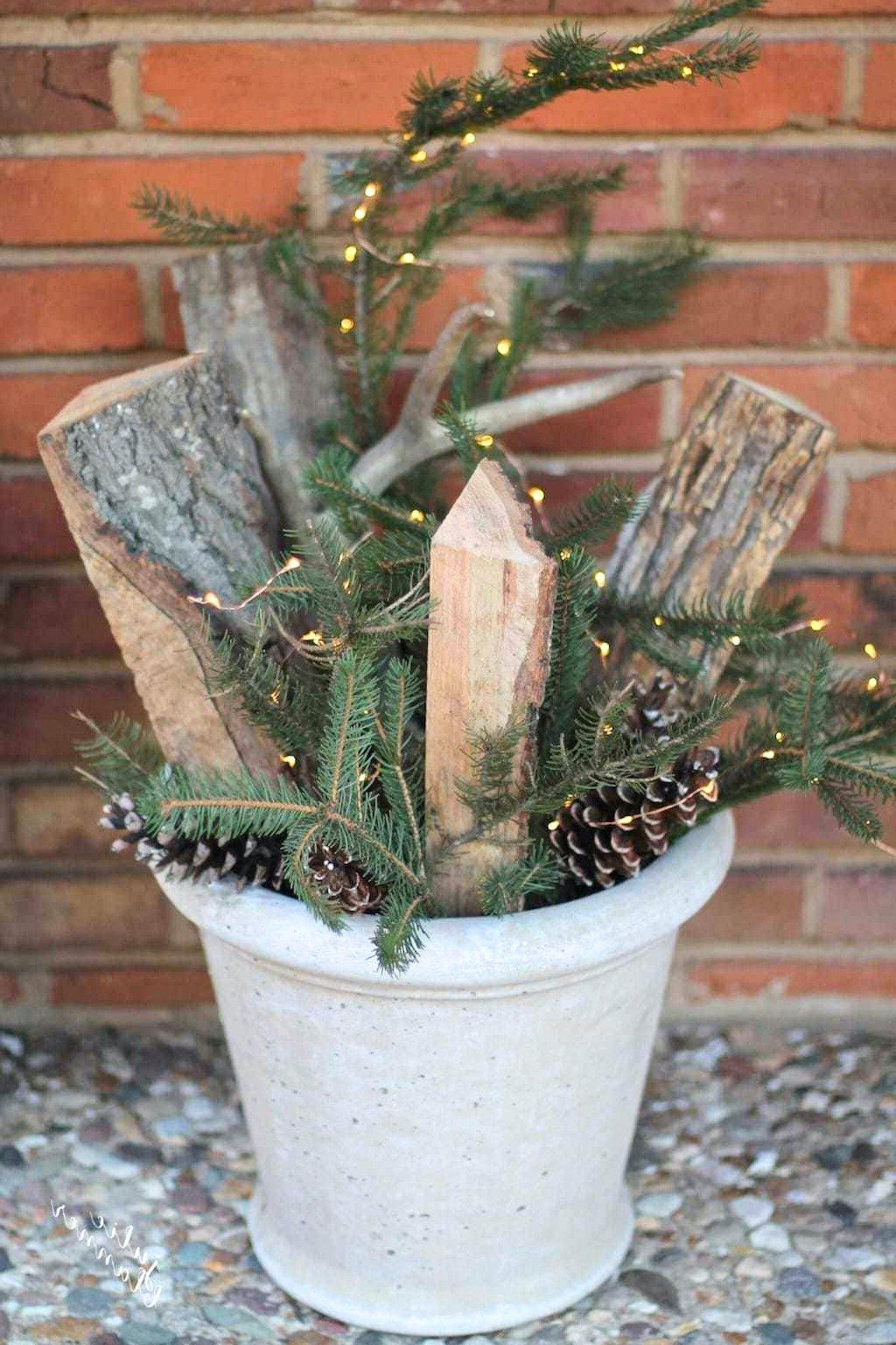 Ein winterlicher Verandakübel voller Brennholz, immergrünen Pflanzen, Geweihen und funkelnden Lichtern.