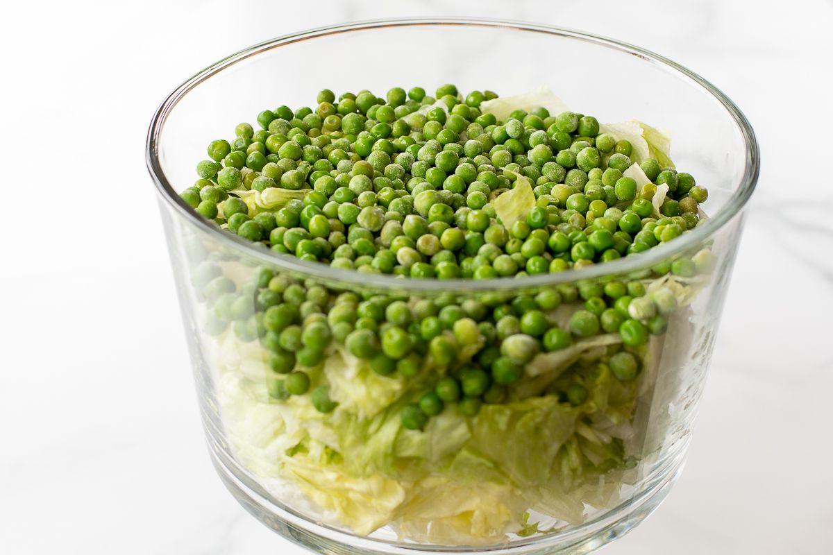Gehackter Salat mit Erbsen in einer Glasschale.