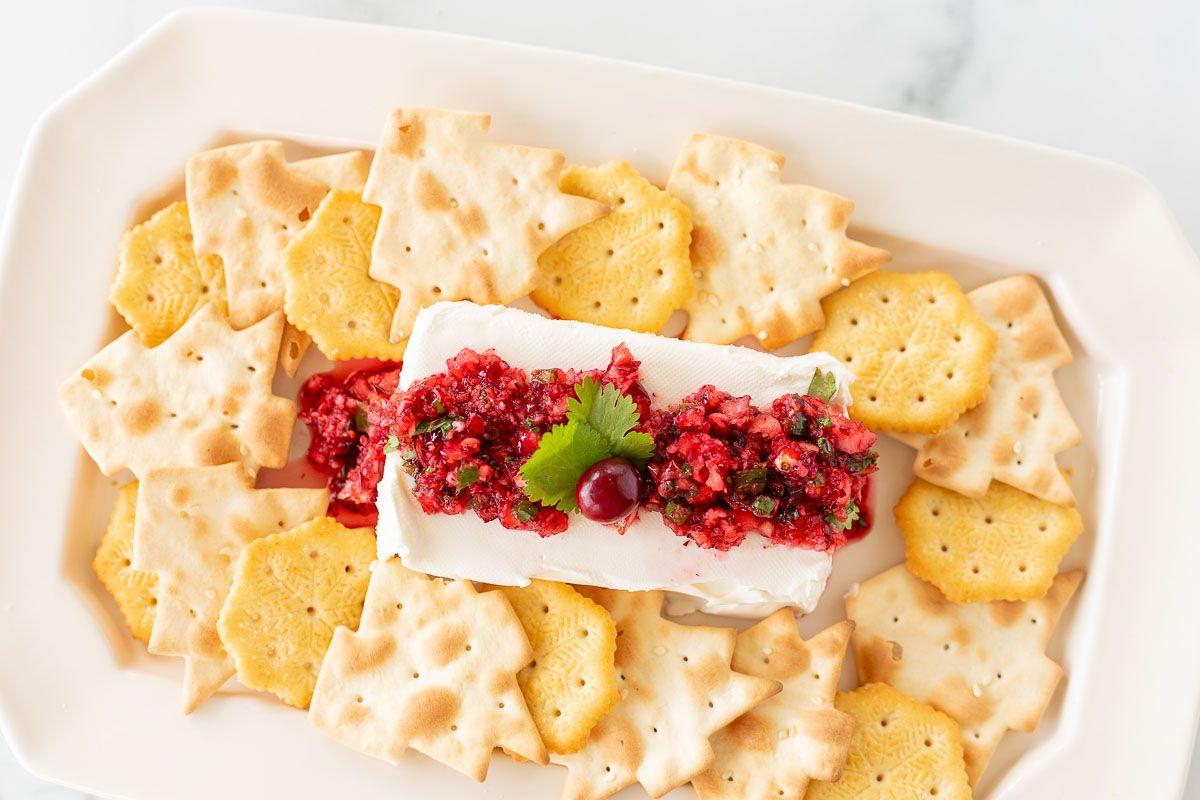 Cranberry-Salsa 9 Ein Teller voller Cracker, die Cranberry-Salsa auf einem Block Frischkäse umgeben