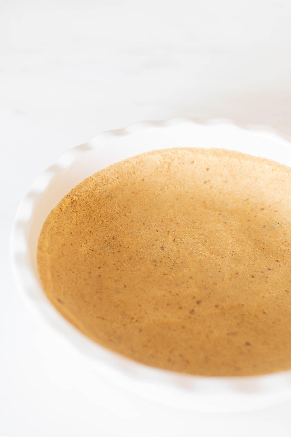 shortbread pie crust Ein Shortbread-Kuchenboden, in eine weiße, geriffelte Keramik-Kuchenform auf einer Marmoroberfläche gepresst