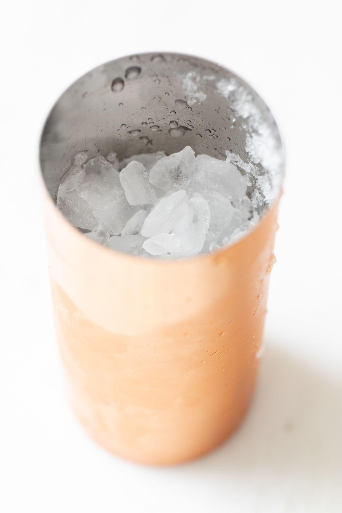 Eine kupferfarbene Cocktailshaker, gefüllt mit Crushed Ice.