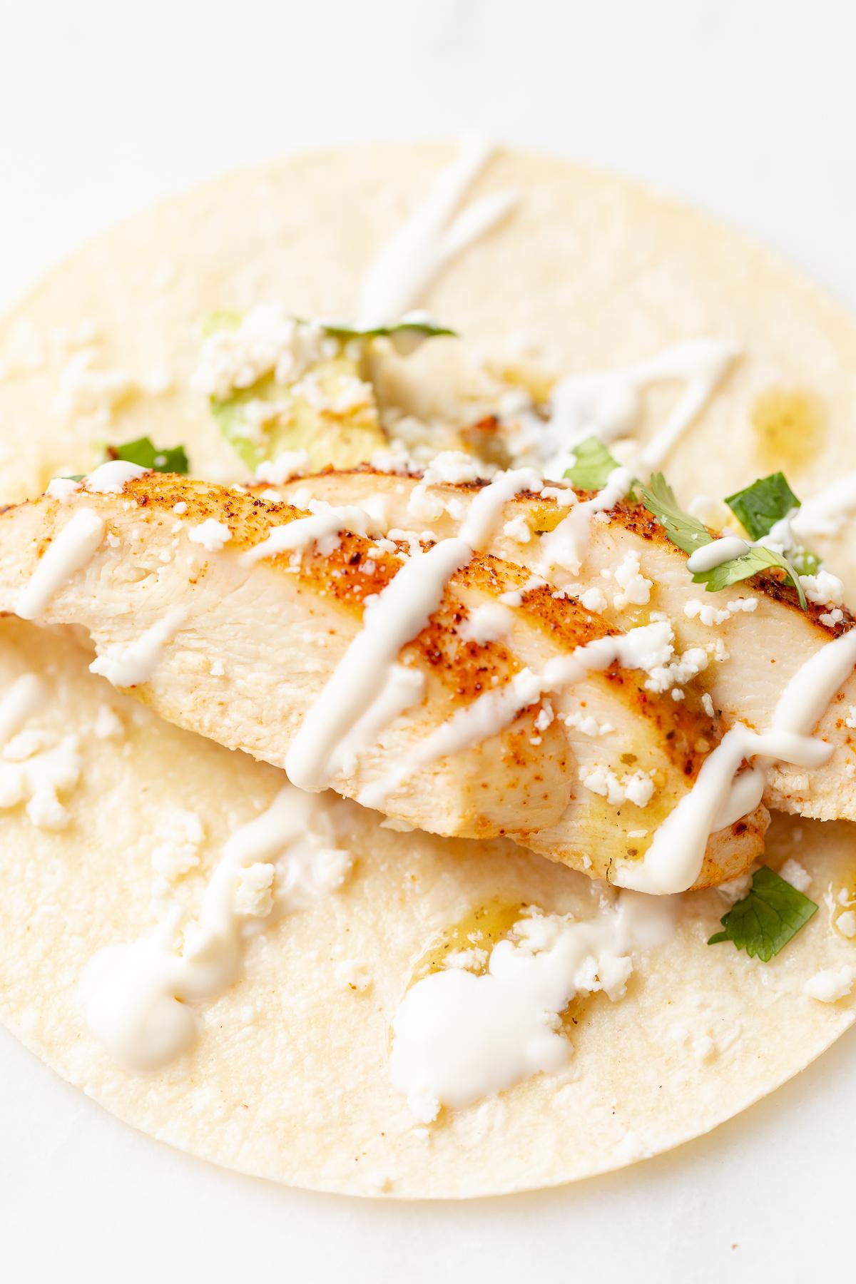 Weiche Hähnchen-Tacos 9 Hähnchen-Tacos in Mais-Tortillas auf einer weißen Oberfläche.