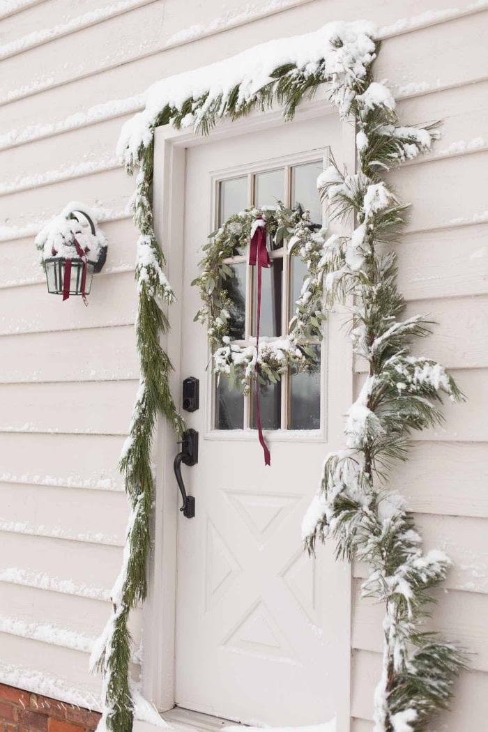 Weihnachtliche Türdekorationen 9 Weihnachtstürdekoration mit Schnee bedeckt an einem Haus