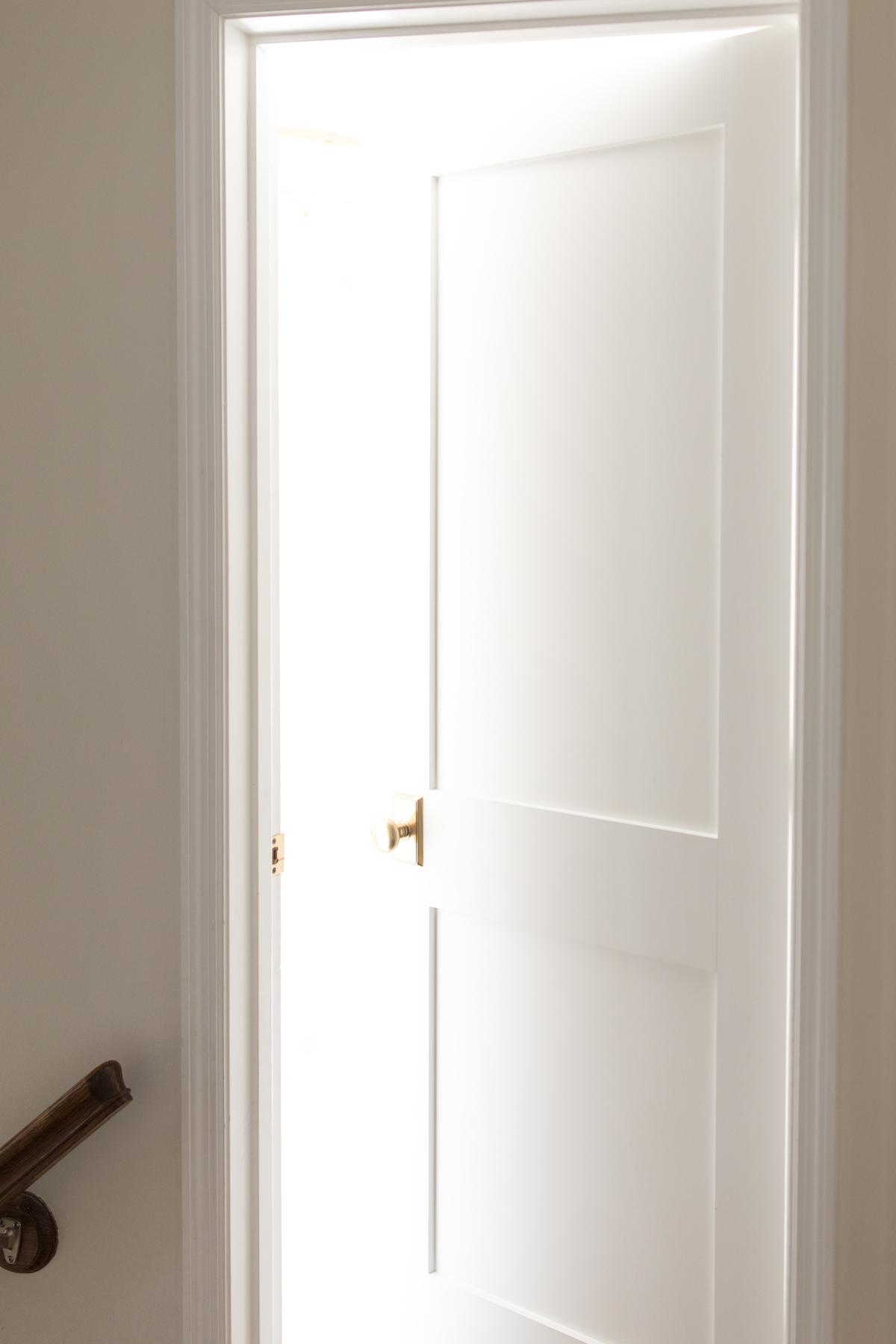 Innentüren streichen 10 Eine teilweise geöffnete weiße Holztür, durch die Licht aus dem Inneren fällt.