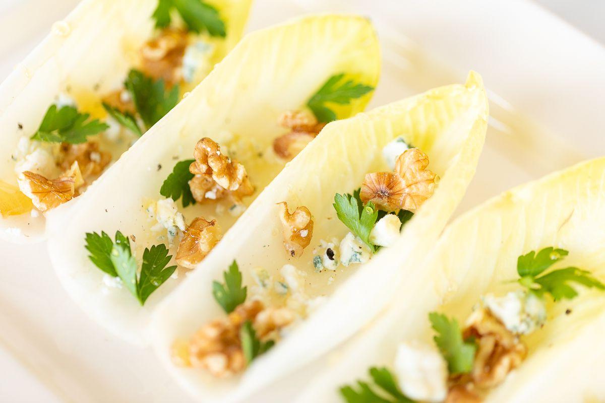 Hand-Endiviensalat 10 Ein Chicorée-Salat auf einer weißen Platte angerichtet.
