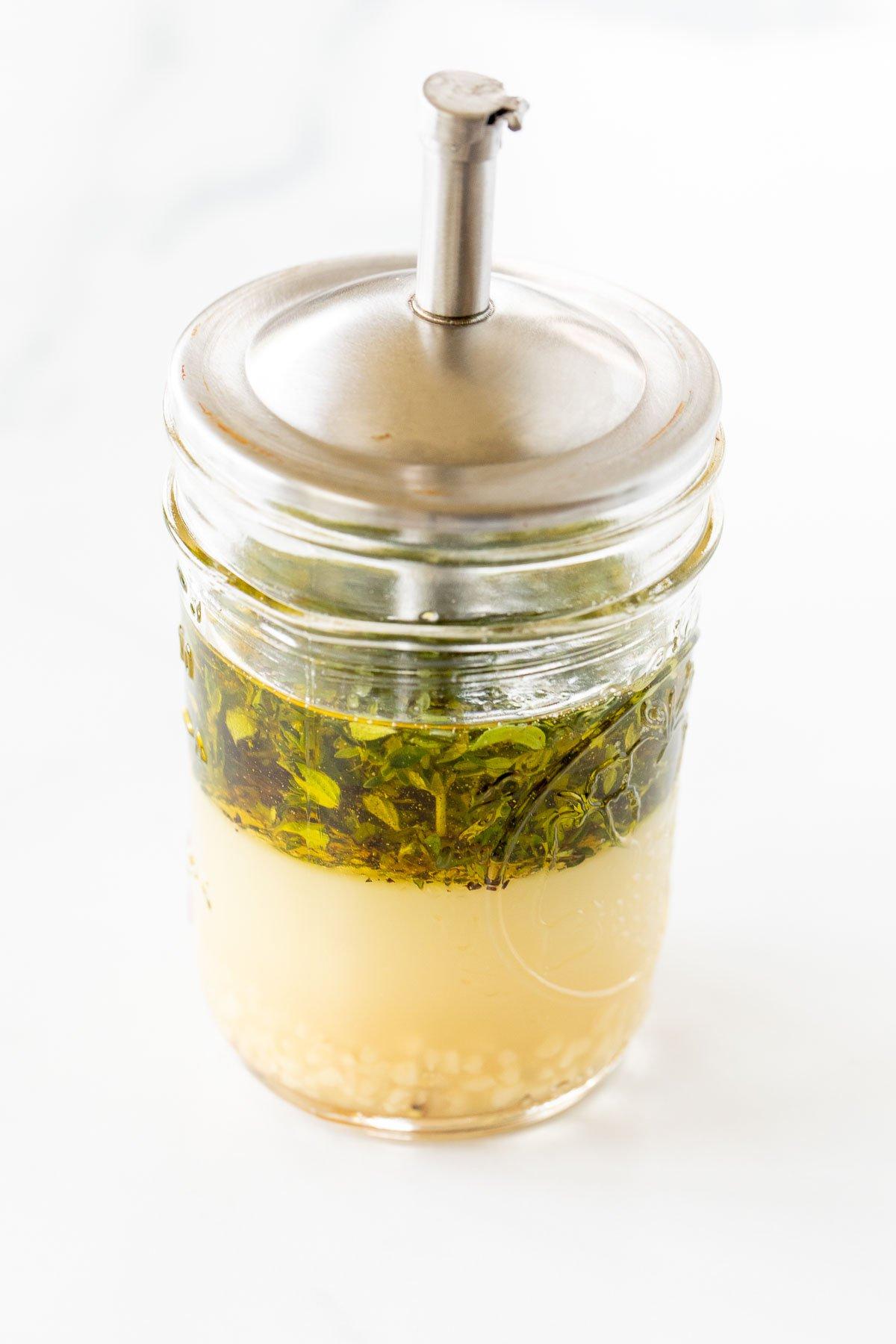 Griechische Hähnchen-Marinade in einem Glasgefäß mit silbernem Deckel.