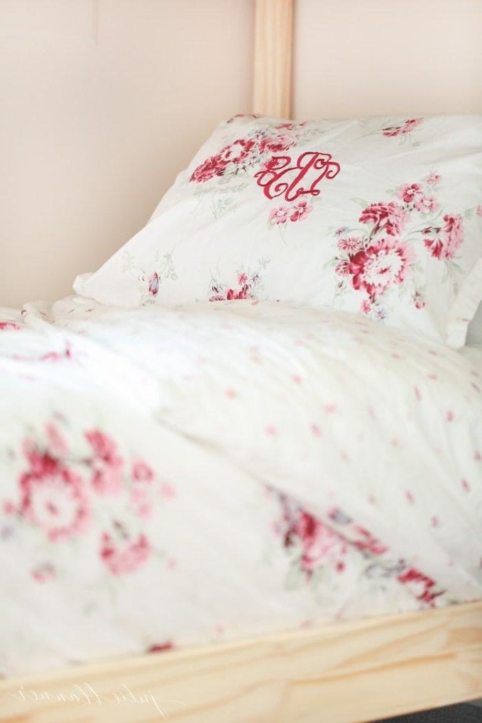 Mädchenetagenbett 10 Eine Nahaufnahme von femininer rosa Bettwäsche neben einem Massivholz-Etagenbettrahmen.
