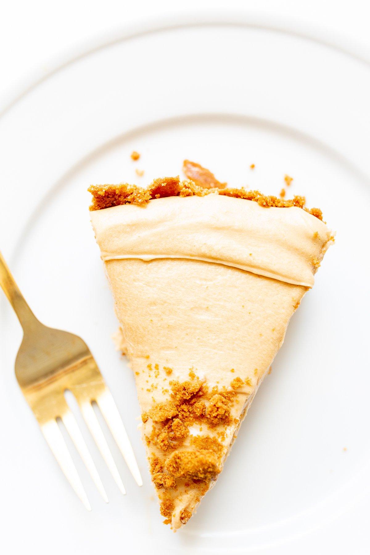 Spekulatius-Keksboden 10 Eine Scheibe No-Bake Keksbutter-Käsekuchen auf einem weißen Teller.