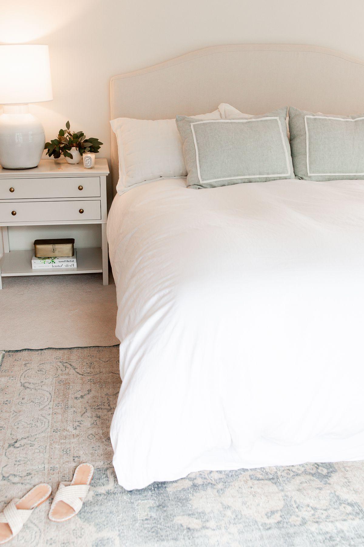 Ein Schlafzimmer mit weißer Bettwäsche und einfacher Nachttischdekoration