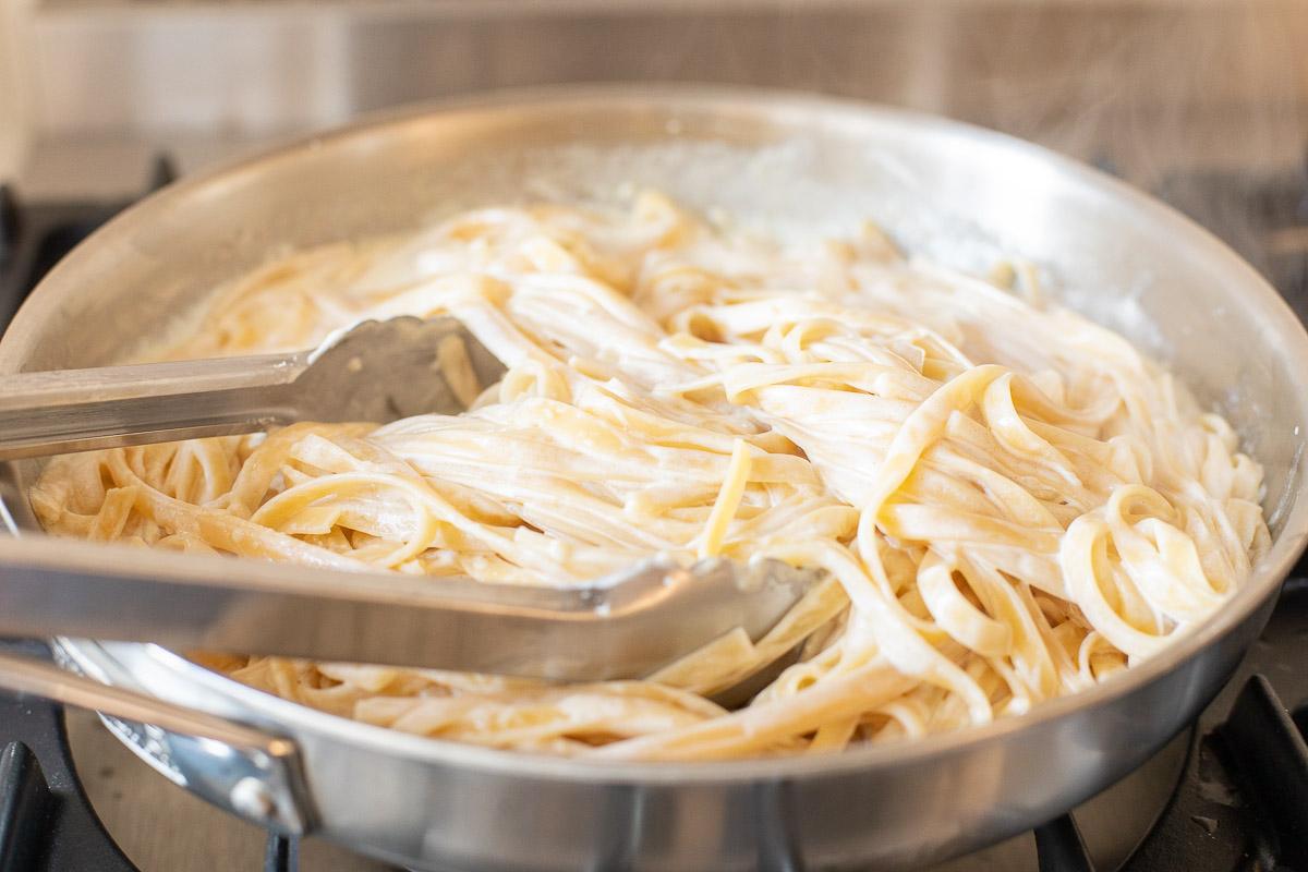Wie man Nudeln aufwärmt 10 Ein Edelstahlkochtopf auf einem Herd, gefüllt mit Pasta. Das Bild ist Teil eines Tutorials zum Aufwärmen von Pasta.