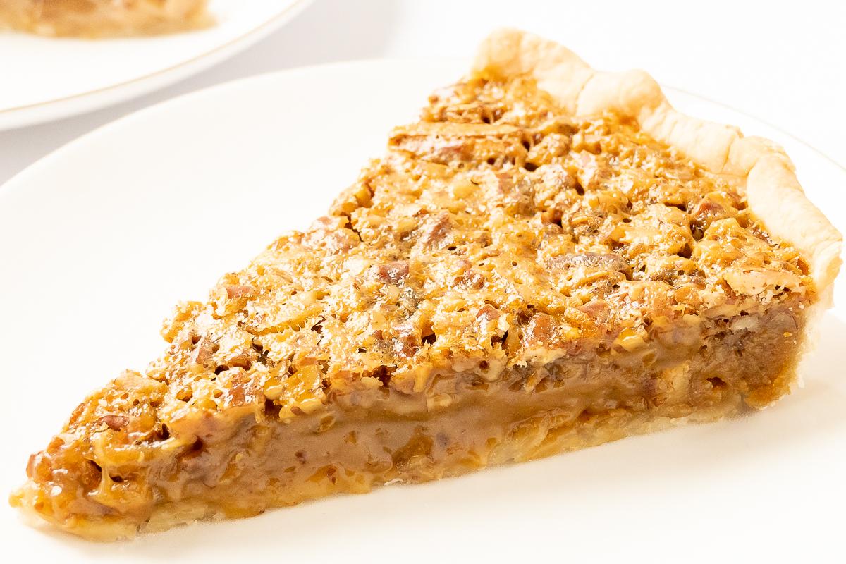 Eine köstliche Scheibe Karamell-Pekannusskuchen auf einem Teller, bereit für den Genuss.