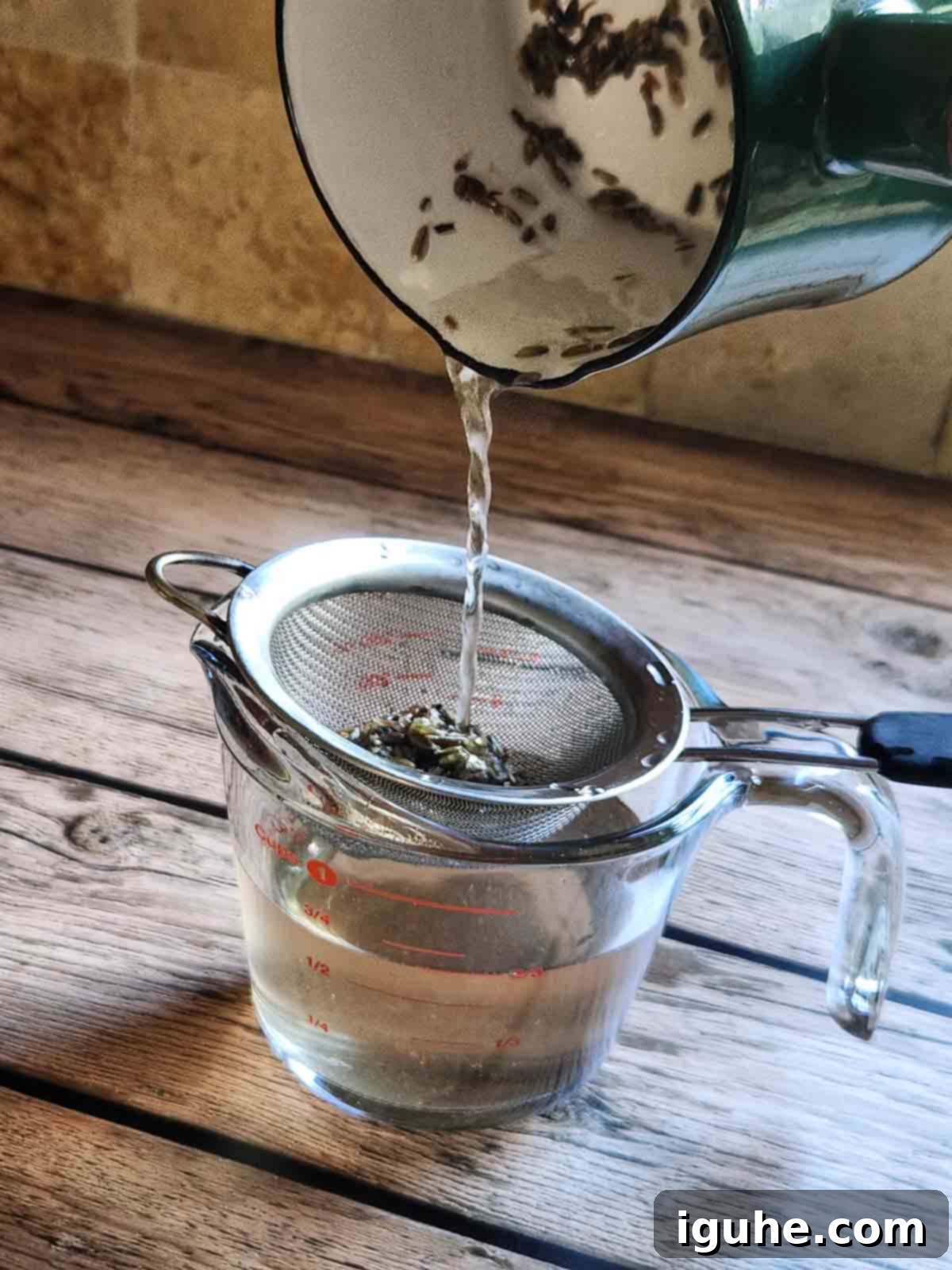 Signature Lavender Lemonade 4 Straining lavender simple syrup into a clear glass.