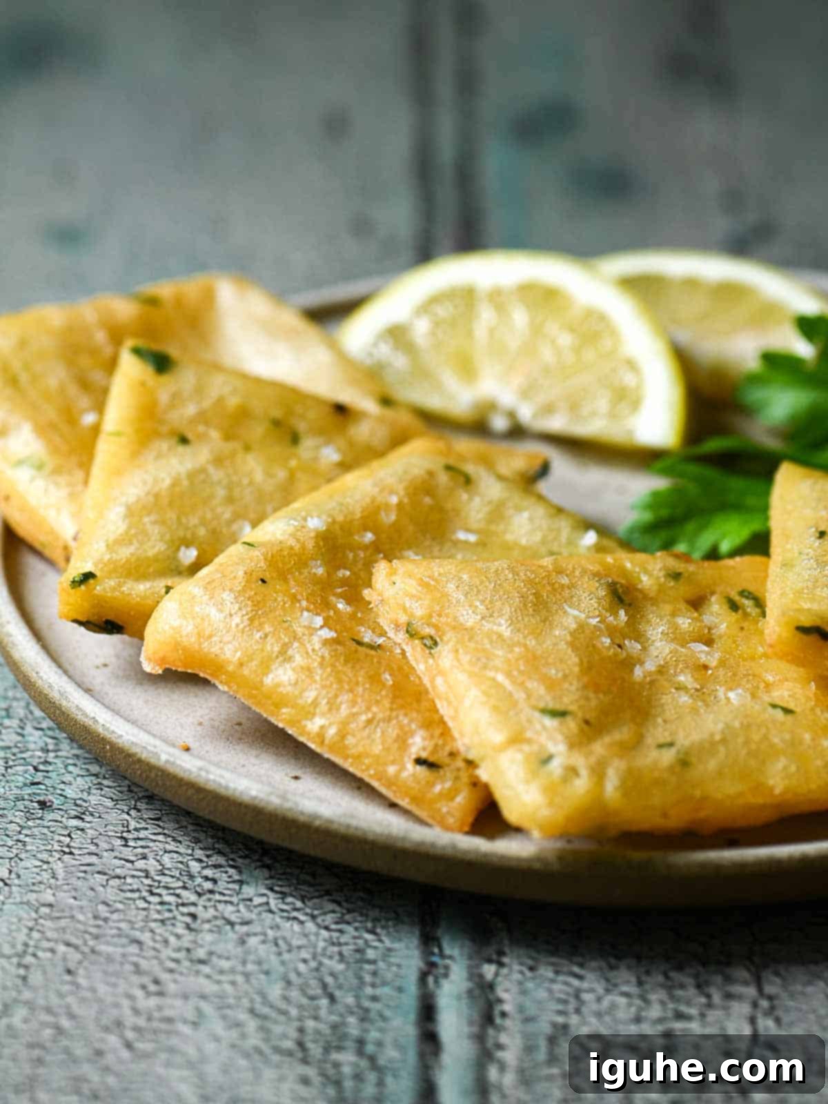 Chickpea fritters in a white plate with lemon wedges.