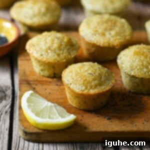 Zesty Lemon Poppy Seed Gems 9 Six perfect mini muffins arranged on a rustic wood board with a fresh lemon next to them, evoking a sense of cozy, homemade goodness.